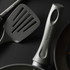 Close-up of grey Salter frying pan handle and spatula on dark background