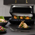 Salter electric grill with chicken and broccoli inside, plates of salad and lamb in front