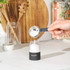 Black matte salt or pepper grinder in hand, shown from side with button on top
