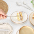 Hand holding fork with slice of sponge cake on cream stoneware plate, with coffee and cutlery