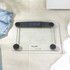 Glass digital bathroom scale with black accents on tile floor