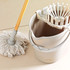 White mop with wooden handle next to beige bucket and wringer