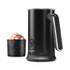 Black electric milk frother with handle next to cup of frothed hot chocolate