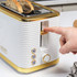 White and gold two-slice toaster on kitchen counter, modern ribbed design.