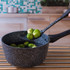 Black speckled saucepan with brussels sprouts on slotted spoon in kitchen