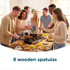 Eight wooden spatulas shown with friends cooking around a tabletop grill
