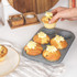Set of non-stick grey baking trays with assorted baked goods, chips and roasted veg