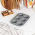 Set of non-stick grey baking trays with assorted baked goods, chips and roasted veg