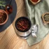Stainless steel coffee grinder with lid open and whole coffee beans inside, on wooden surface
