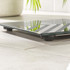 Black glass bathroom scale with striped pattern, shown on tiled floor