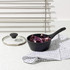 Black saucepan with glass lid, containing chopped red cabbage on kitchen worktop