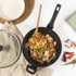 Black and white speckled non-stick cookware set including saucepans and frying pans on a kitchen counter.