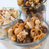 Gourmet snack mix with coated popcorn, chocolate balls and pretzels in glass bowls
