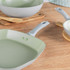Set of five green non-stick frying pans and griddle on kitchen worktop