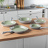 Set of four light green non-stick frying and grill pans on kitchen counter