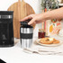 Black Salter coffee maker on countertop with hand placing lid on stainless steel travel mug