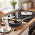Non-stick egg poaching pan with four sections and glass lid on kitchen hob