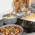 Set of three grey saucepans with glass lids, one with rice, one with curry, on kitchen counter