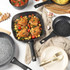 Non-stick frying pan with crispy chicken thighs, roasted vegetables, and tomatoes