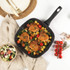 Non-stick frying pan with crispy chicken thighs, roasted vegetables, and tomatoes