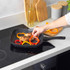 Set of three black and white speckled non-stick pans, two with cooked food, on a white kitchen counter