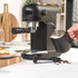 Black espresso machine on kitchen counter with coffee scoop and mug