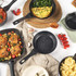 Set of non-stick black frying pans with food, shown from above on kitchen table