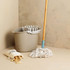 Beige mop bucket with wringer, white string mop, and cloth bag of wooden pegs