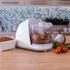 White electric mini food chopper with chopped vegetables, shown on a kitchen worktop