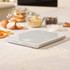 White digital kitchen scale on worktop with baking ingredients in background