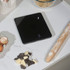 Glass bowl of brown sugar on digital kitchen scale, hand holding bowl, baking scene