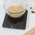 Black digital kitchen scale stored in drawer beside wooden utensils