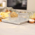 Digital kitchen scale with butter in bowl, baking ingredients and egg on white surface