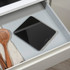 Black digital kitchen scale with a white ramekin and eggshells on top, on a countertop