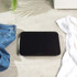 Black glass bathroom scale on tiled floor with jeans and white towel beside