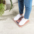 Person in white trainers and jeans standing on pink bathroom scale