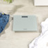 Digital bathroom scale with glass platform on tiled floor