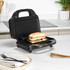 Black panini press open on kitchen counter with toasted sandwich inside.