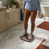 Person in cream robe stepping on gold analogue bathroom scales in modern bathroom