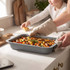 Grey roasting tin with cooked casserole being served in a home kitchen setting