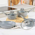 Set of grey speckled non-stick saucepans and frying pan with glass lids on kitchen worktop