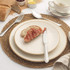 Stainless steel knife, fork, and spoon set on a plate with bread and jam for breakfast.