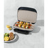 Electric grill with open lid showing vegetable and halloumi skewers on plates