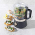 Grey food processor bowl on black and silver base, close-up in modern kitchen.