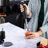 Hand blender mixing tomatoes in beaker in modern kitchen