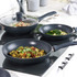 Set of three non-stick black frying pans on hob, each with food, for UK kitchenware product listing