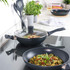 Non-stick black frying pan and wok with cooked food on a modern kitchen hob
