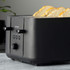 Black Salter 4-slice toaster with seeded bread, shown on kitchen surface.