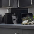 Black metal tea caddy set on kitchen worktop, open tin with herbal tea bags visible.