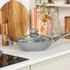 Grey non-stick frying pan with glass lid on kitchen counter